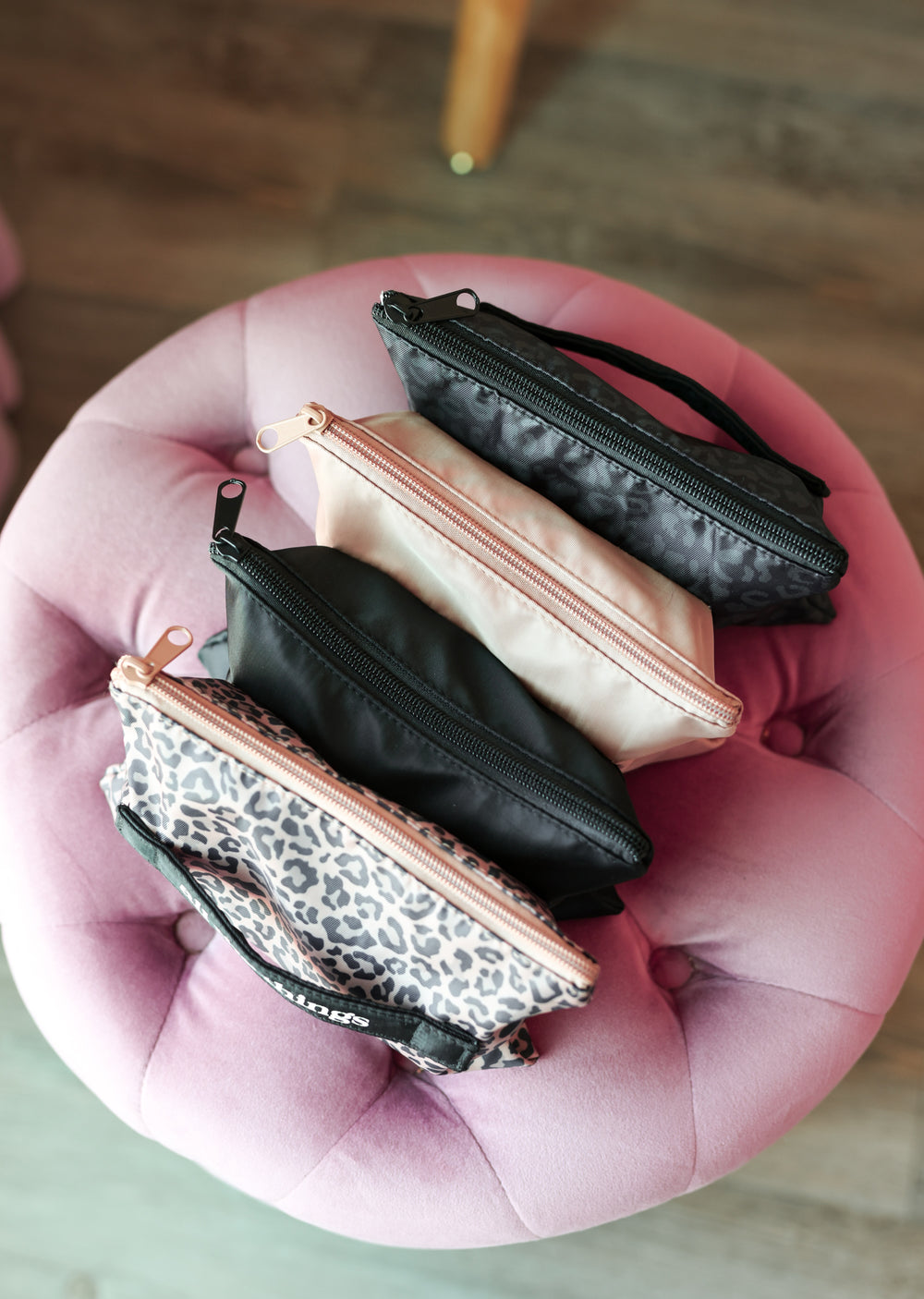 Four small pouches on a pink cushion with a blurred background