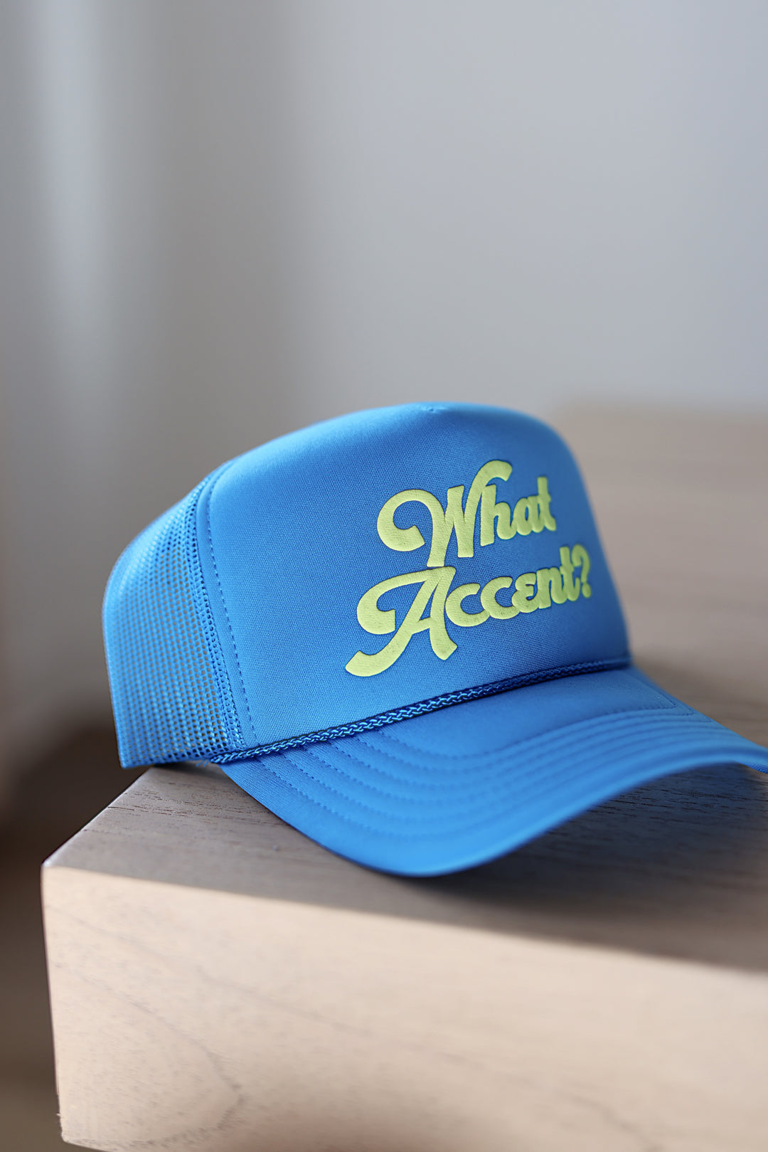 Blue cap with 'What Accent?' text on a wooden surface
