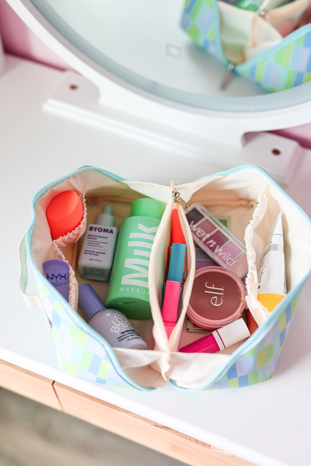 Colorful cosmetic bag with makeup products, featuring a blue and green checkered design.