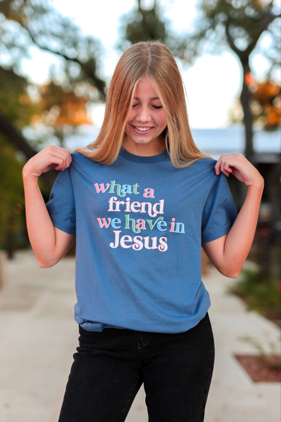 Person wearing a blue t-shirt with a message, standing outdoors.