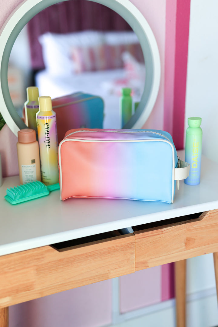 Colorful makeup bag on a vanity table with various beauty products.