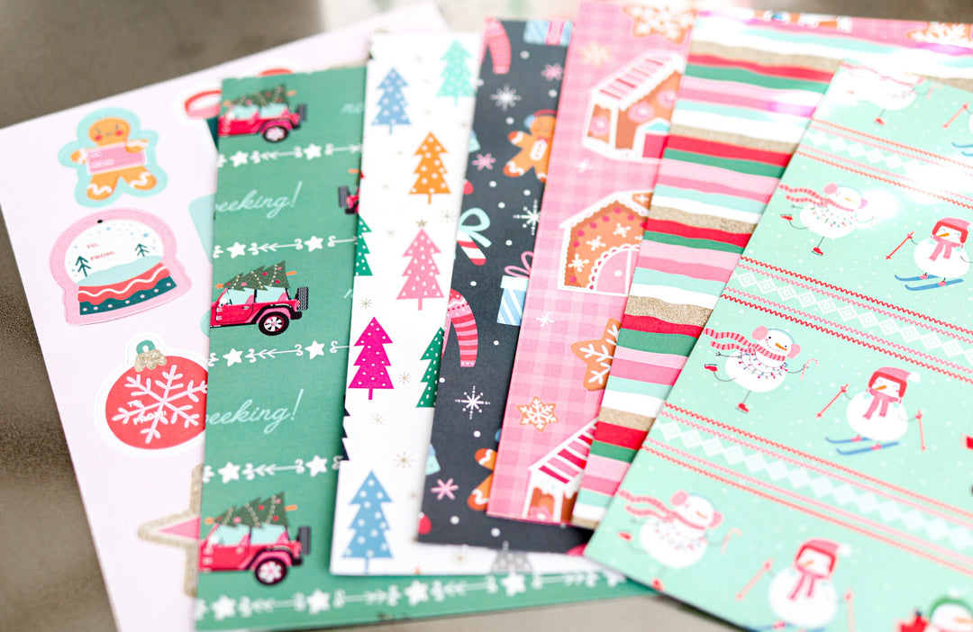 Colorful holiday-themed scrapbook paper set featuring snowmen, Christmas trees, and festive designs.