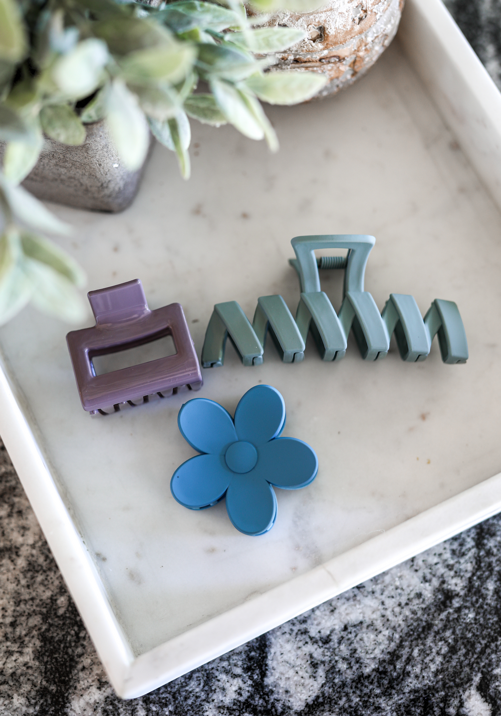 Set of three colorful hair clips: purple rectangle, teal claw, and blue flower design, perfect for stylish hairstyles.